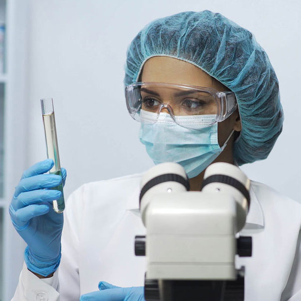 lab tech in PPE holding a test tube of liquid