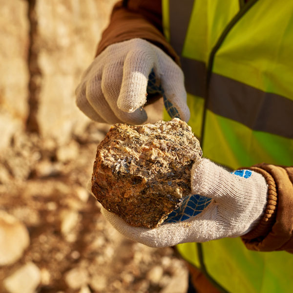 Person wearing gloves holding a chunk of coal